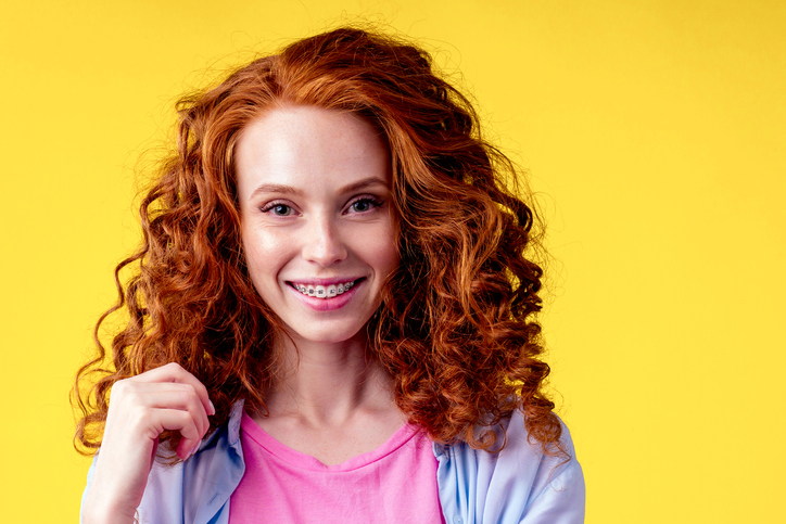 curly-haired, red-headed woman wearing braces