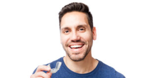 Man holding Invisalign tray and smiling